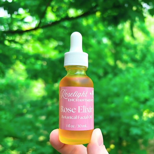 Bottle of Roselight Enchantments Rose Elixir Botanical Facial Oil held against a green leafy background