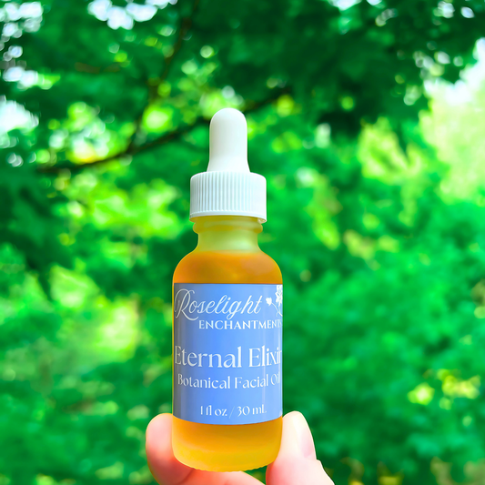 Bottle of Roselight Enchantments Eternal Elixir Botanical Facial Oil held against a green leafy background.
