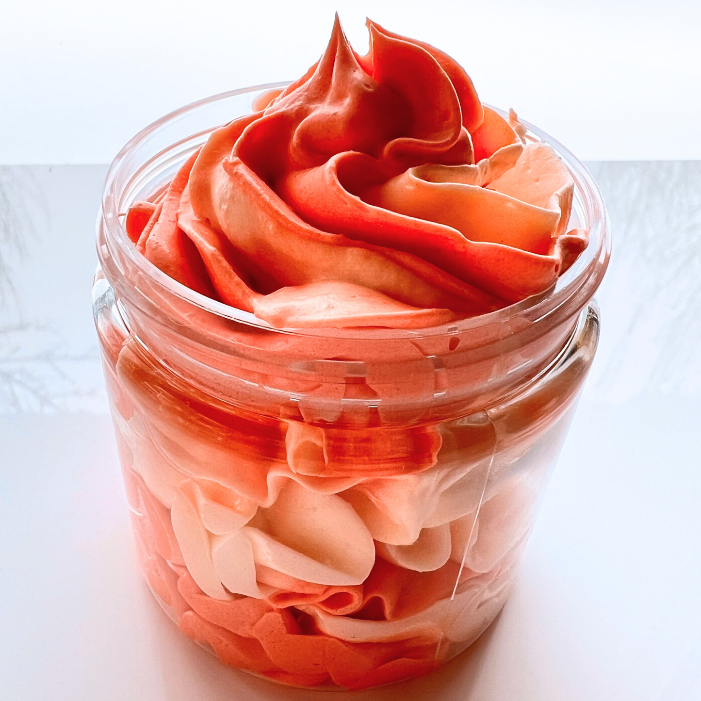 Close-up of orange and white whipped body butter in jar.
